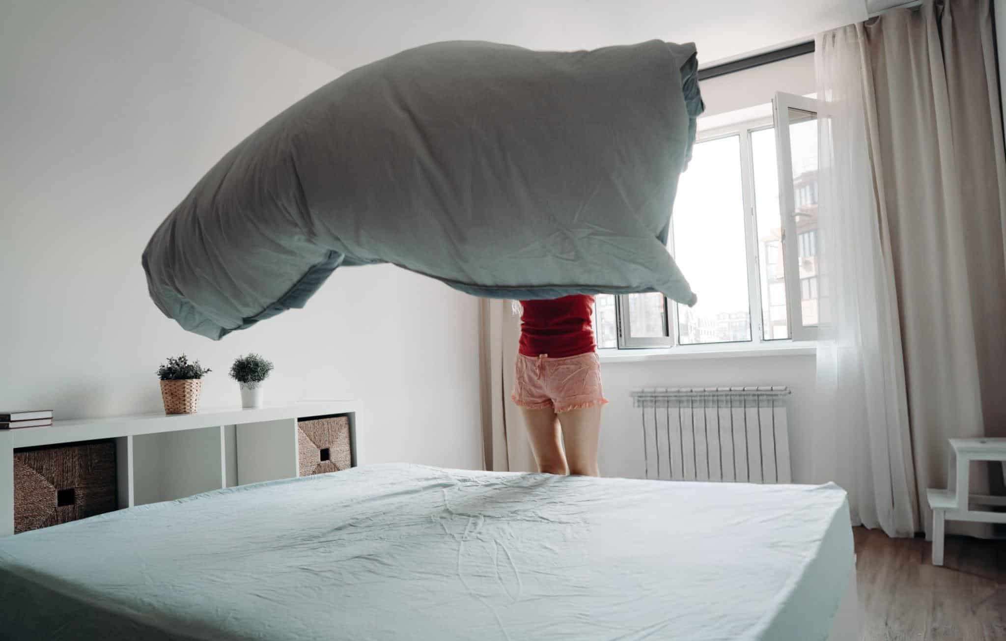 A-woman-makes-her-bed-the-sheet-billowing-in-the-air-above-the-mattress-ab035db375873340e450dda227503e33.jpg
