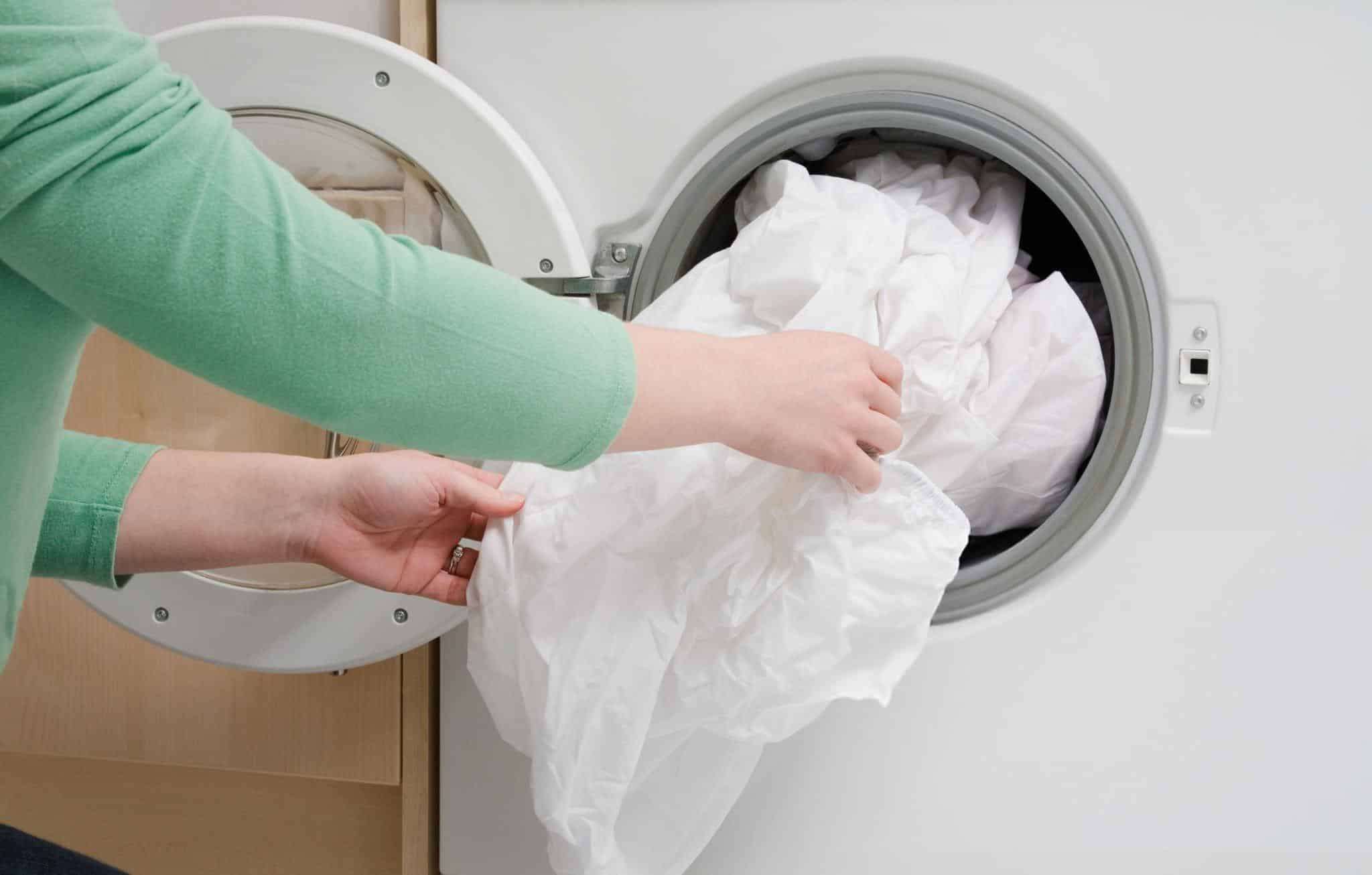 Woman-taking-sheet-from-washing-machine-0fedd22bf8193c33adc39b1d17d77e1f.jpg